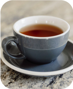 Blue ceramic cup and saucer with a dark liquid on a marble surface