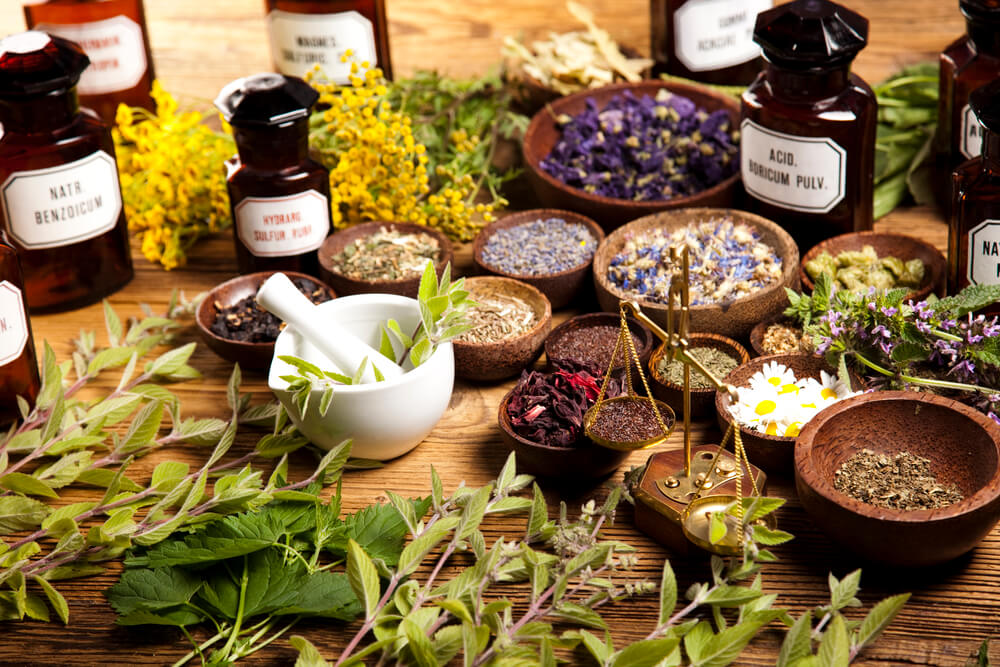herbs on wooden table with mortar and pestle