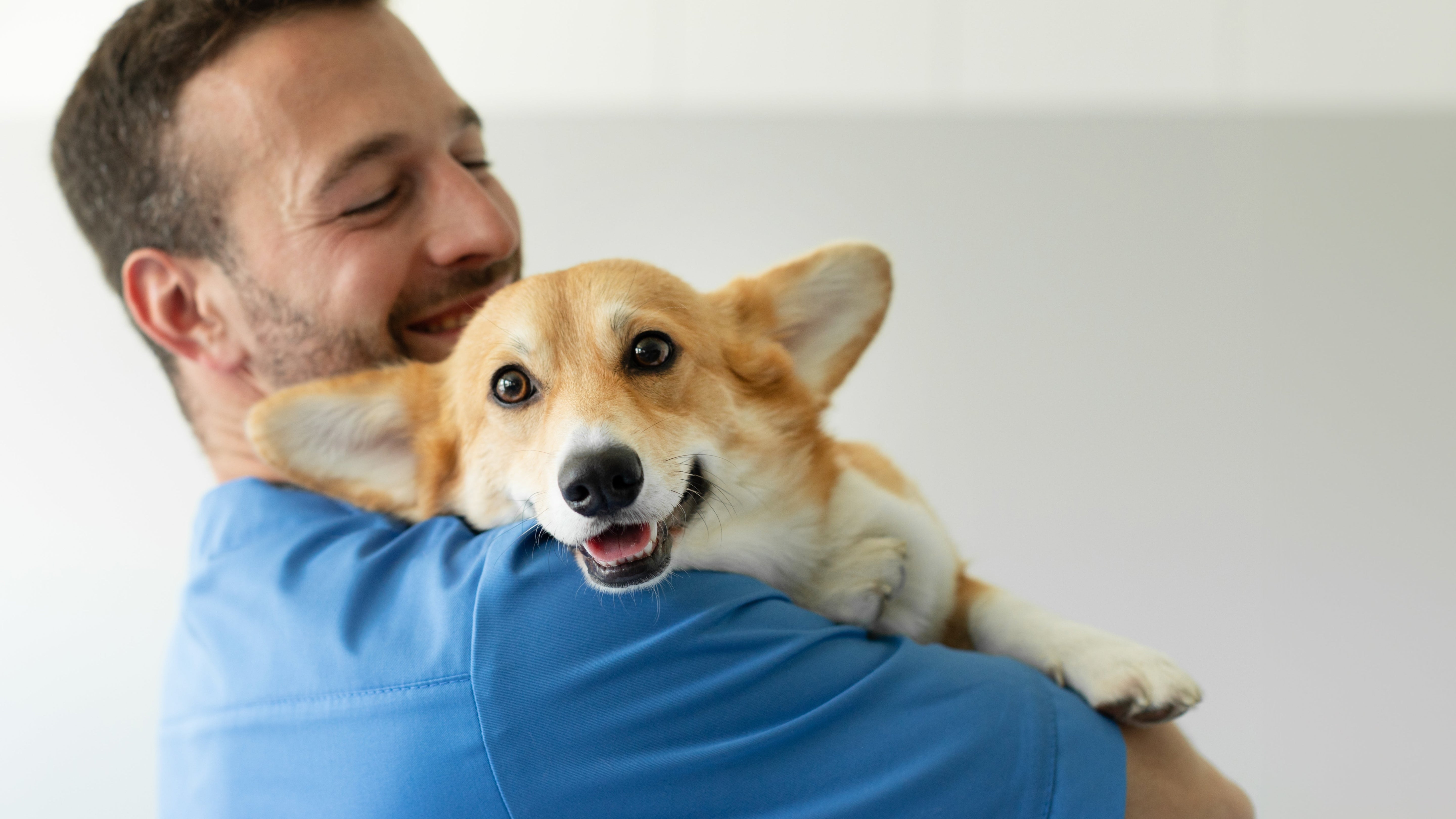 Man holding Corgi Dog and smiling