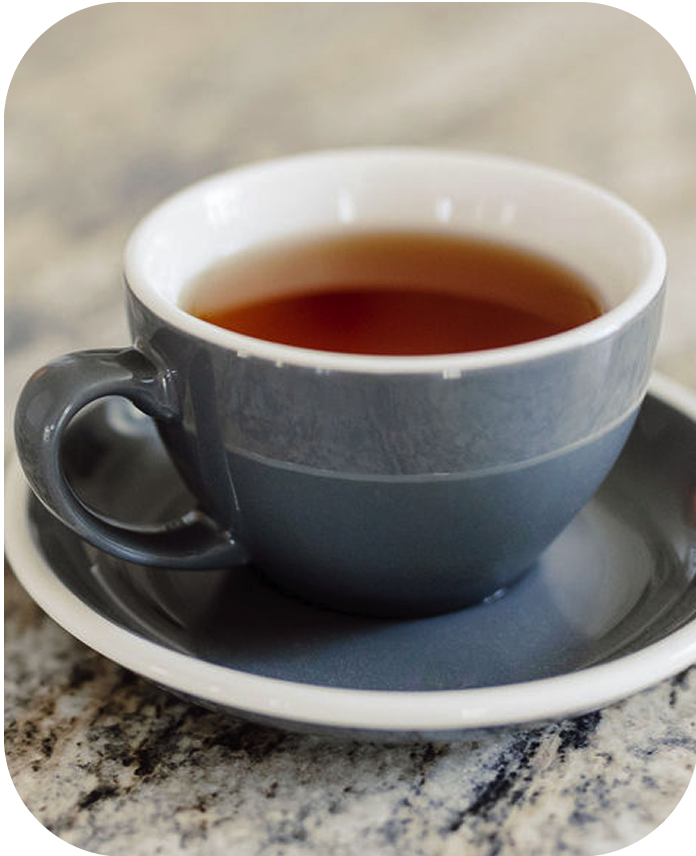 Blue ceramic cup and saucer with a dark liquid on a marble surface